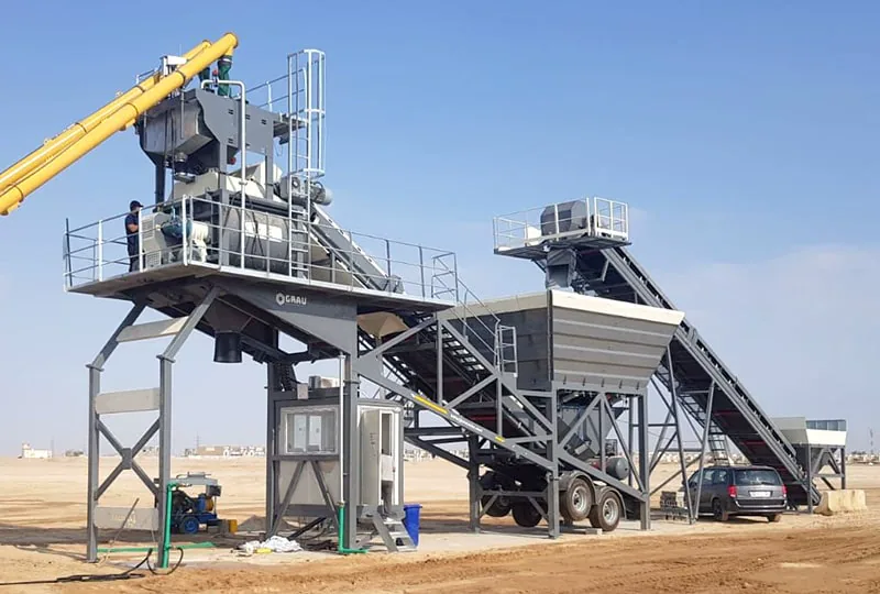 GRAU G100M mobile concrete plant on an open site in Karbala, Iraq, with a worker on the mixer platform