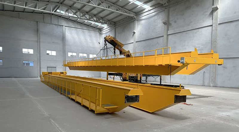 Poutres jaunes de pont roulant dans le nouveau hall d’usine vide de GRAU, l’une levée par des chaînes au bras d’une grue