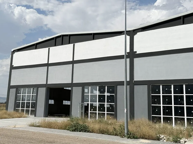 Façade du nouveau bâtiment d’usine de GRAU, gris et blanc, avec de grandes fenêtres et une porte ouverte