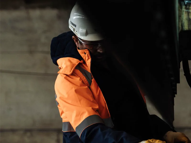 GRAU worker in a hard hat and orange high-visibility jacket at a press in the factory