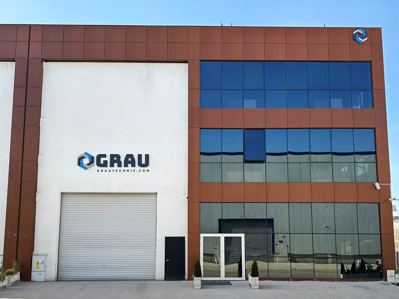 Front of a GRAU factory building, with the company sign over a roller door beside a glazed office block