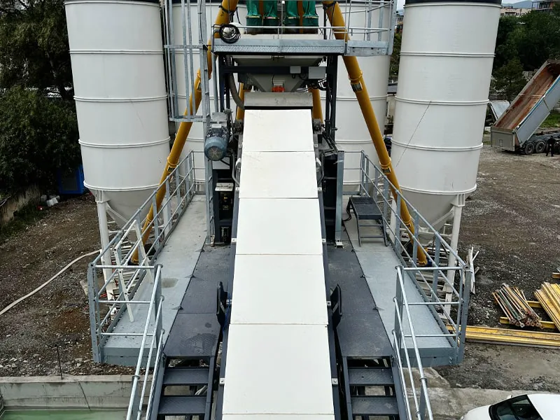 Wide service platforms with handrails either side of a GRAU mobile concrete plant’s transfer conveyor, between silos